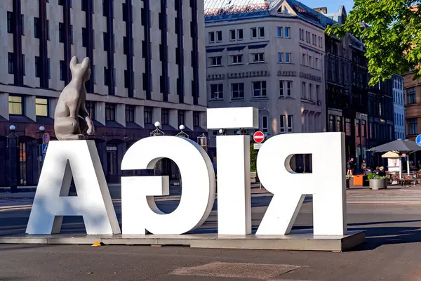 LATVIA, RIGA, 25 Mayıs 2025: Özgürlük Anıtı 'nın arka planında Akış adlı filmden bir kediyle birlikte büyük beyaz harflerle RIGA. Letonya 'nın başkenti Riga. 