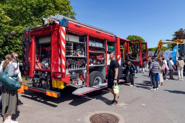 LATVIA, RIGA, HAZİRAN, 12, 2025: Ziyaretçiler Riga, Letonya 'da açık hava ticari araç sergisinde bir itfaiye aracının içine bakıyorlar