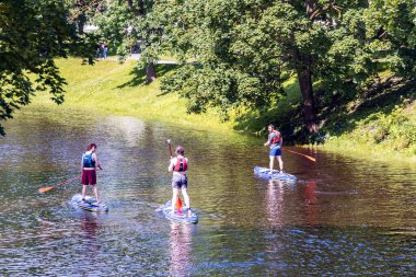 LATVIA, RIGA, JULY, 15, 2025: Riga, Letonya 'da şehir kanalında kürek çeken aktif adamlar. Sportif yaşam tarzı kavramı