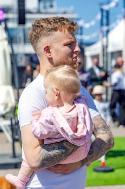 LATVIA, RIGA, JULY, 16 Temmuz 2025: Küçük çocuğuyla birlikte sıcak bir yaz günü Letonya, Riga 'da yürüyüş yapan genç bir baba. Genç aile kavramı.