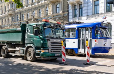 LATVIA, RIGA, JULY, 15 Temmuz 2025: Riga, Letonya 'da yol onarım bariyerlerinin kaldırılmasını bekleyen bir tramvay ve kamyon. Riga Şehir Taşımacılığı.