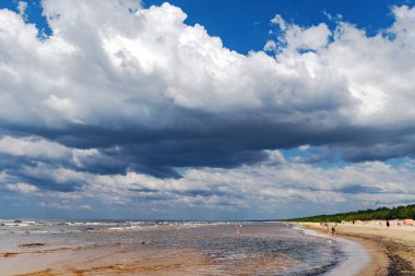 LATVIA, RIGA, JULY, 25 Temmuz 2025: Sıcak yaz suyu ve insanların yüzdüğü Baltık Körfezi ve Jurmala, Letonya 'da gökyüzünde büyük kümülüs bulutları