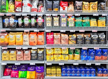 LATVIA, RIGA, JULY, 25, 2025: Riga, Letonya 'da bir süpermarketin raflarında farklı dünya üreticilerinin kahve çekirdekleri paketleri bulunan büyük bölüm