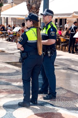 İSPAN, ALICANTE, MAYIS, 17, 2025: İkili olarak çalışan belediye polisi, İspanya 'nın Alicante kentindeki sokaklarda düzeni koruyor
