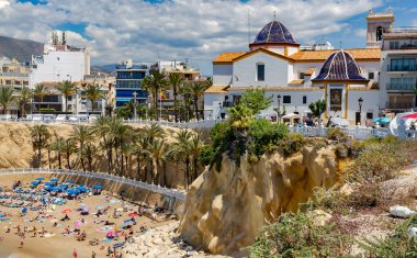 İspanya, BENIDORM, MAYIS, 21, 2025: Benidorm, İspanya 'da antik mimari ve dağların arka planında tatilcilerle Playa del Mal Pas' ın yukarısından görüş.