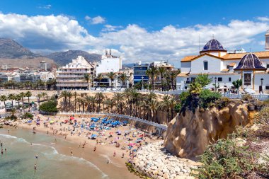 İspanya, BENIDORM, MAYIS, 21, 2025: Benidorm, İspanya 'da antik mimari ve dağların arka planında tatilcilerle Playa del Mal Pas' ın yukarısından görüş.