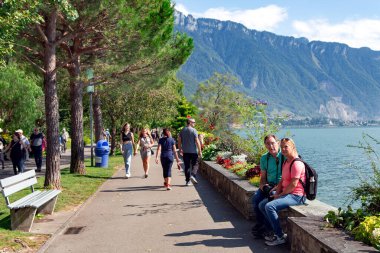 SWitzERLAND, MONTREUX, AĞUSTOS, 28, 2021: Montreux rıhtımlarında uzun çam ağaçları ve çiçek sınırları boyunca yürü Cenevre Gölü, Montreux, İsviçre.