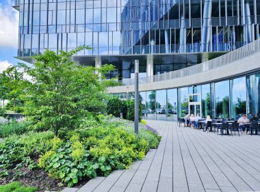 LATVIA, RIGA, AUGust, 19, 2025: Camdan panelleri, güzel peyzajı ve Letonya Riga, Letonya 'da bir yazlık kafe terası olan modern bir binanın mimarisi.