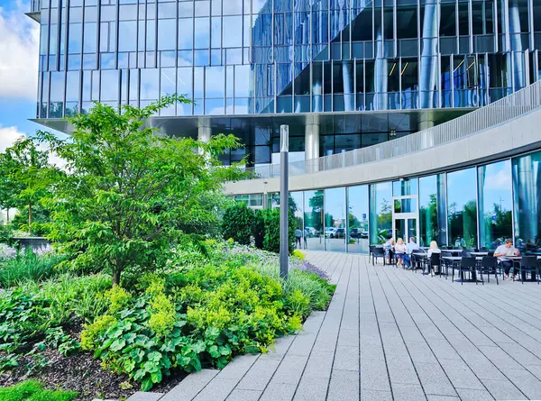 LATVIA, RIGA, AUGust, 19, 2025: Camdan panelleri, güzel peyzajı ve Letonya Riga, Letonya 'da bir yazlık kafe terası olan modern bir binanın mimarisi.