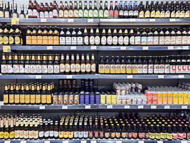 LATVIA, RIGA, AUGust, 31, 2025: Riga, Letonya 'daki bir alışveriş merkezindeki çeşitli dünya üreticilerinin cam şişe biralarıyla dolu büyük bir bölüm