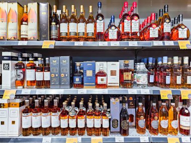 LATVIA, RIGA, AUGust, 31, 2025: Stockmann hipermarketindeki raflarda konyak, konyak ve armagnastlar bölümü, Riga. Letonya.
