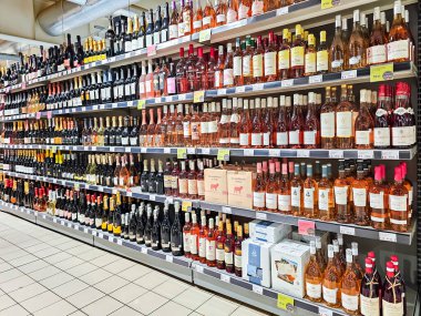 LATVIA, RIGA, AUGust, 30, 2025: Riga, Letonya 'daki SKY ve More hipermarketinde çeşitli kırmızı, gül şarapları, şampanya, vermut ve diğer alkollü içeceklerle dolu büyük bir bölüm.