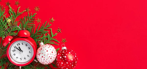 多色のクリスマスボールと赤い紙の背景に木の枝と目覚まし時計 新年の5分前 創作グリーティングカード — ストック写真