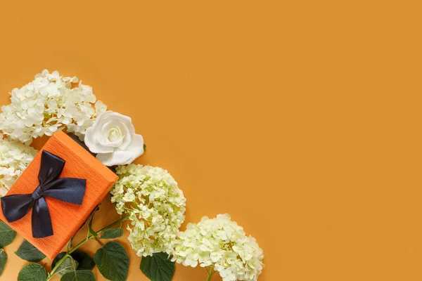 白い紫陽花のギフトボックスとオレンジの紙の背景にバラの花 休日のための概念的なポストカード — ストック写真