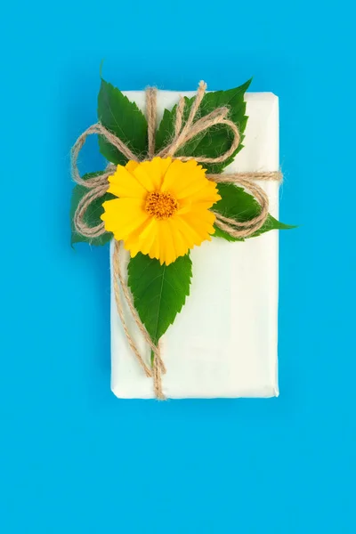 Gifts in paper wrapping, set of vintage yellow package paper for decoration. Bouquet of yellow  chamomile on blue vintage background.