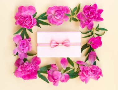 Sarı arka planda hediye paketleri olan güzel pembe şakayık demetleri. Tatil için tebrik kartı. Metin için kopyalama alanı olan yaratıcı arkaplan.