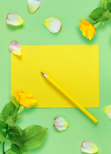 在一张绿色的桌子上 一束美丽的黄色玫瑰和花瓣 你的课本和铅笔 图库图片