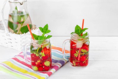 Beyaz ahşap masada güzel havlu taze olgun çilek içecek ile iki bardak