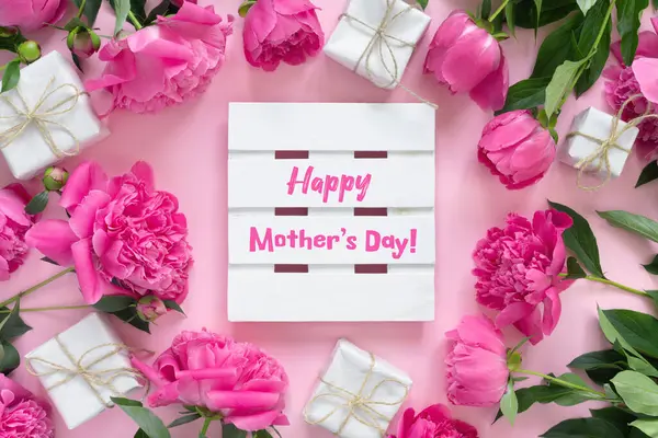 紙の包装にギフトボックスと美しいピンクの牡丹の花束 丸い花のフレーム 白い木の板とテキスト Happy Mother Day ストック画像