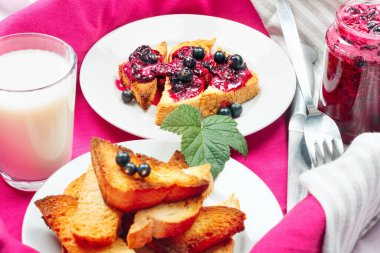 Lezzetli tost ekmeği ev yapımı frenk üzümü reçeli ve süt parlak kırmızı masa aralığında.