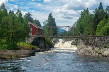 Norveç 'in vahşi Heddola nehri üzerinde bir kulübe ve eski bir metal köprü.