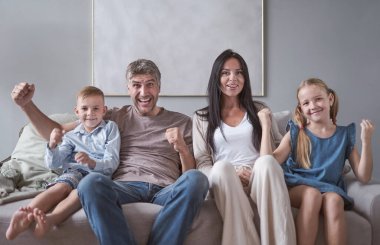 Aile oturma odasında oturuyor ve gülümsüyor.