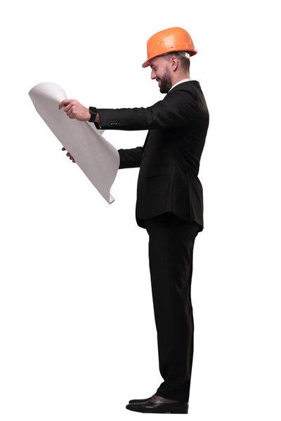 in full growth. businessman in helmet looking at new drawings . isolated on white background