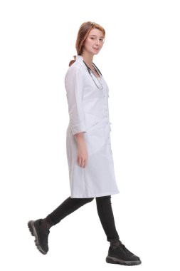 Kameraya doğru yürüyen kadın doktor beyaz bir arka planda izole bir şekilde gülümsüyor.