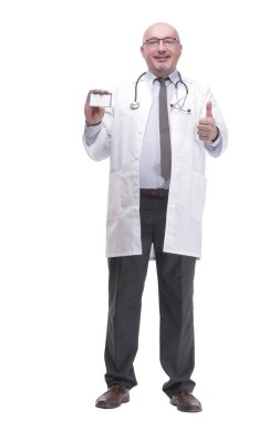 in full growth. qualified mature doctor showing his visiting card. isolated on a white background.