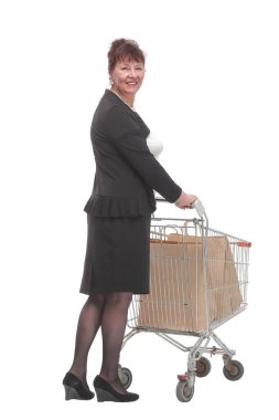 Alışveriş arabalı olgun bir kadın beyaz arka planda stüdyoda dikiliyor.