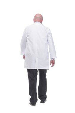 in full growth. confident mature doctor in a white coat striding forward .isolated on a white background.