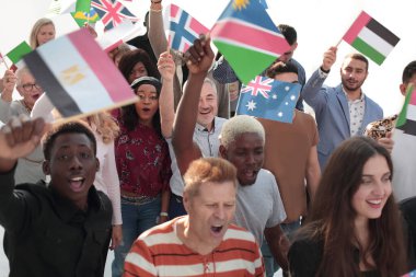 Farklı ülkelerin bayraklarıyla ilerleyen çok ırklı bir grup mutlu genç insan.