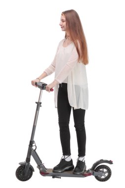 Genç, mutlu bir kadın arka planda motorunun yanında duruyor kameraya bakıyor ve bisikletini tutuyor.