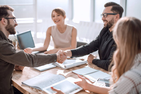 улыбающиеся деловые партнеры, пожимающие руки на деловой встрече. бизнес концепция