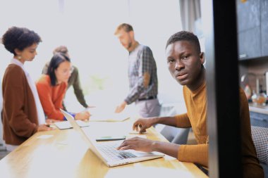 Afro-Amerikan iş adamı ofiste dizüstü bilgisayarla çalışıyor.