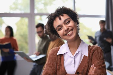 Başarılı iş kadını yaratıcı ofiste durup gülümserken kameraya bakıyor.