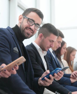 Kapat. Bir grup genç iş adamı akıllı telefon ekranlarına bakıyor..