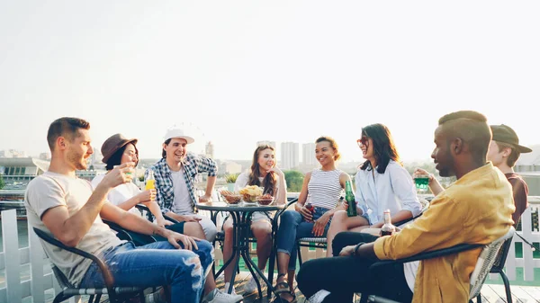 友人の多民族のグループは オープンエア パーティーを飲んで 話して 笑って楽しんで夏と良い会社をことです 大都市とお祝いのコンセプト — ストック写真