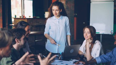 Kadın takım lideri loft office uluslararası şirketin iş stratejisi tartışırken çok ırklı ekibi konuşuyor. Tartışma, gençler, çalışma alanı ve planlama kavramı.