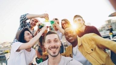 Arkadaşları eğlenirken, elinde kamera olan yakışıklı bir adamın selfie çektiği bir bakış açısı.