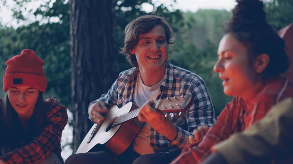 Bonito Jovem Turista Está Tocando Guitarra Sorrindo Enquanto Seus Amigos — Fotografia de Stock