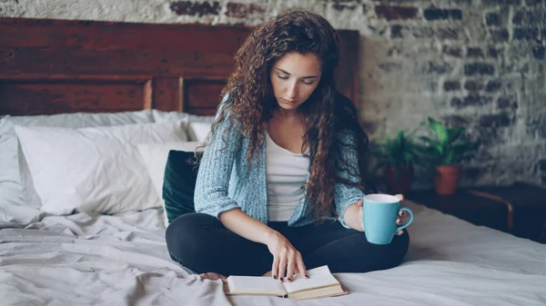 여자는 집에서 침대에 앉아서 즐기는 읽고는 사람들 인테리어 — 스톡 사진