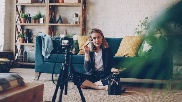 블로거는 메이크업과 아름다움 집에서 바닥에 앉아와 삼각대에 카메라를 비디오를 화장품 — 스톡 사진