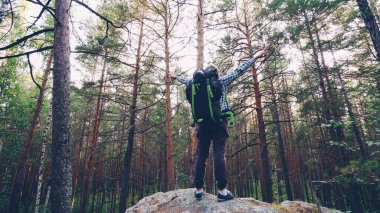 Yakışıklı adam sırt çantası ile turist kıyafeti giymiş başarı kutluyor sonra aşağı trekking eller yükselterek kaya, yukarı tırmanıyor. Kişi, olumlu duygular ve doğa kavramı.