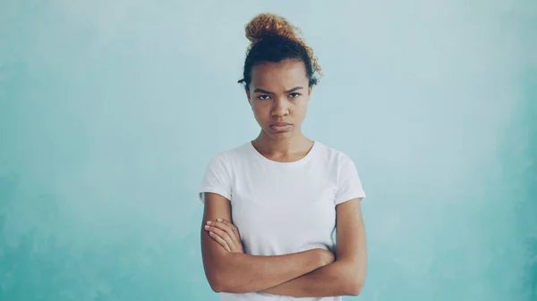 Portrait of angry African American lady looking at camera, frowning and expressing disappointment, anger and disapproval standing with arms crossed and breathing heavily.