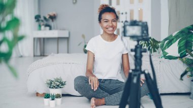Kadın blogger video kamera, gülümseyen ve duygusal evde yatak odası katta oturan konuşurken bakarak videolog için kaydediyor. İnsanlar, teknoloji ve sosyal medya kavramı.