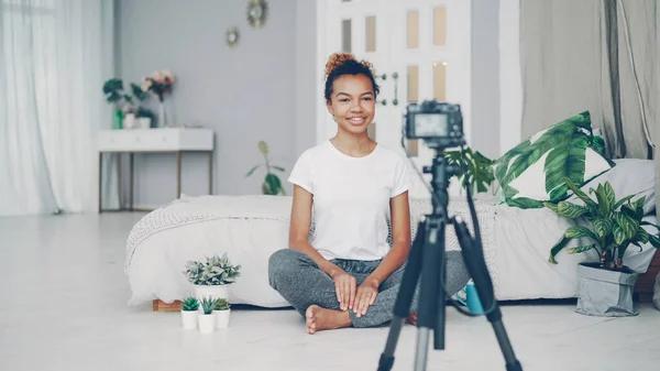 그녀의 아파트의 바닥에 삼각대에 카메라를 얘기에 비디오를 잘생긴 아프리카계 미국인 — 스톡 사진