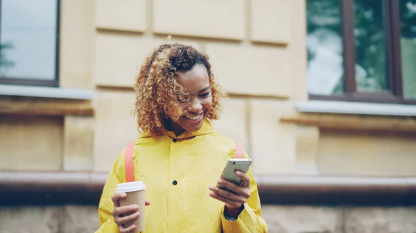 Красивая Афроамериканка Смотрит Экран Смартфона Трогает Счастливой Улыбкой Стоя Улице — стоковое фото