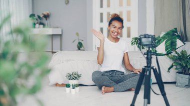 Yaratıcı blogger neşeli genç kadın onu internet blog konuşmak, gülümseyen ve tripod üzerinde kamera seyir için video kaydediyor. Teknoloji, gençlik ve kitle iletişim araçları kavramı.