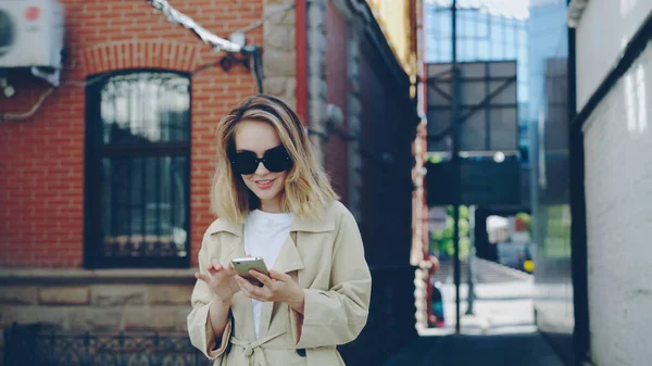 선글라스와 코트에 아가씨 스마트폰 도시에서 거리를 도보로 그것을 사람들 청소년 — 스톡 사진
